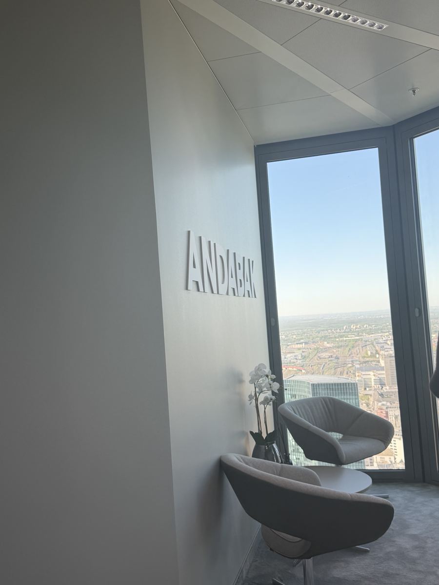 3D-Wandlogo „ANDABAK" an einer Eckwand im Büro im 10. Stock des Hochhauses „The Four" in Frankfurt am Main, mit Sitzgelegenheiten und Panoramafenster mit Blick auf die Stadt