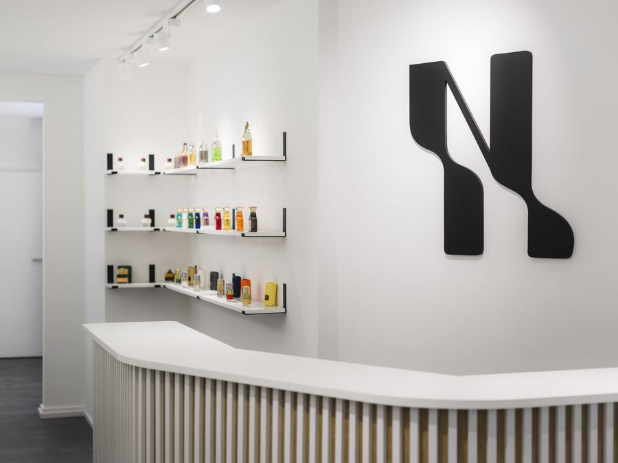 3D-Wandlogo von Nischengold an der Rezeption, im Hintergrund die Parfümregale