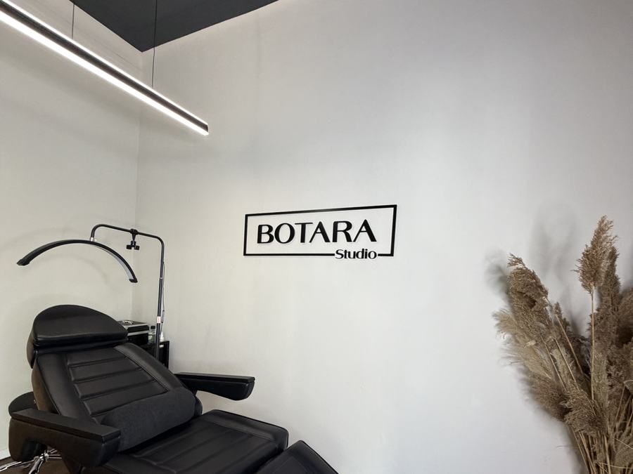 Behandlungsliege im Innenbereich von BOTARA Studio mit Wandlogo und Deko