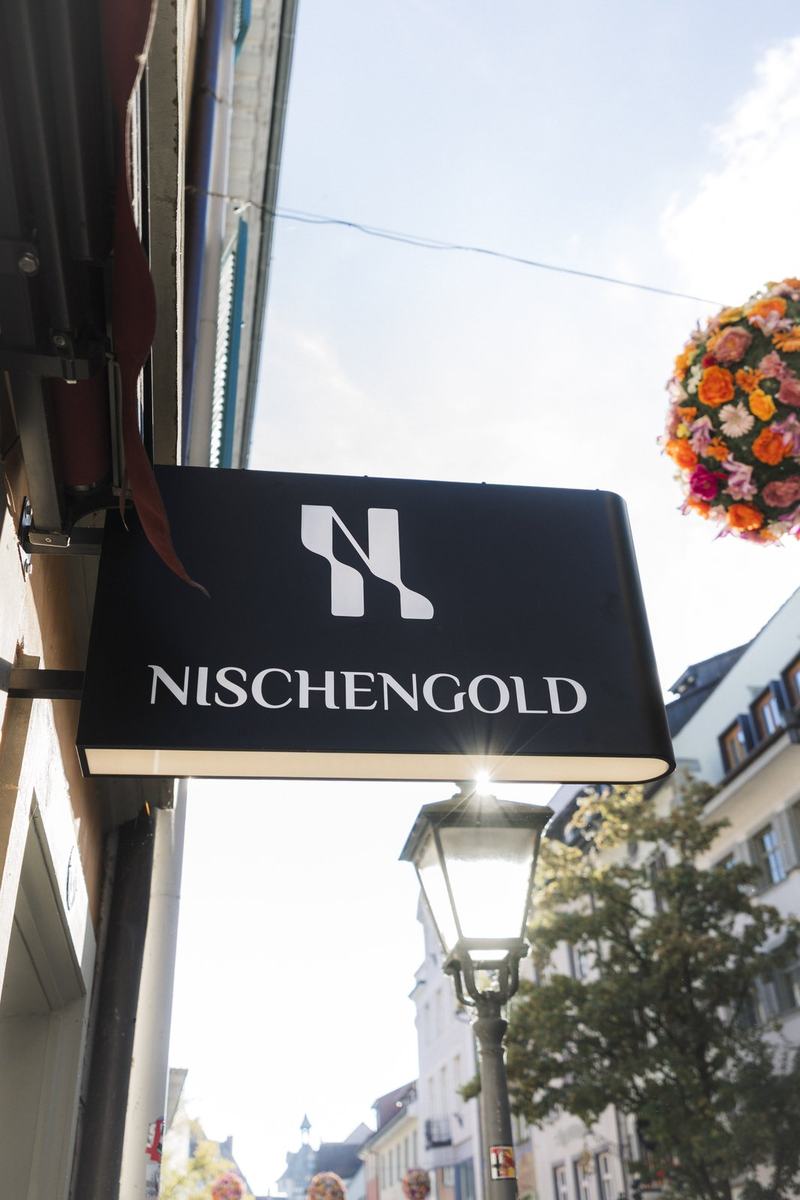 Beleuchtetes Ausleger-Nasenschild mit Logo für die Parfümerie Nischengold in Konstanz