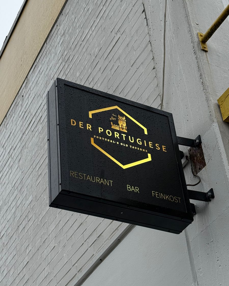 Beleuchtetes, sechseckiges Nasenschild "DER PORTUGIESE / Portugal's Old Taverne / Restaurant Bar Feinkost" an der Fassade in der Hammerstraße, Münster