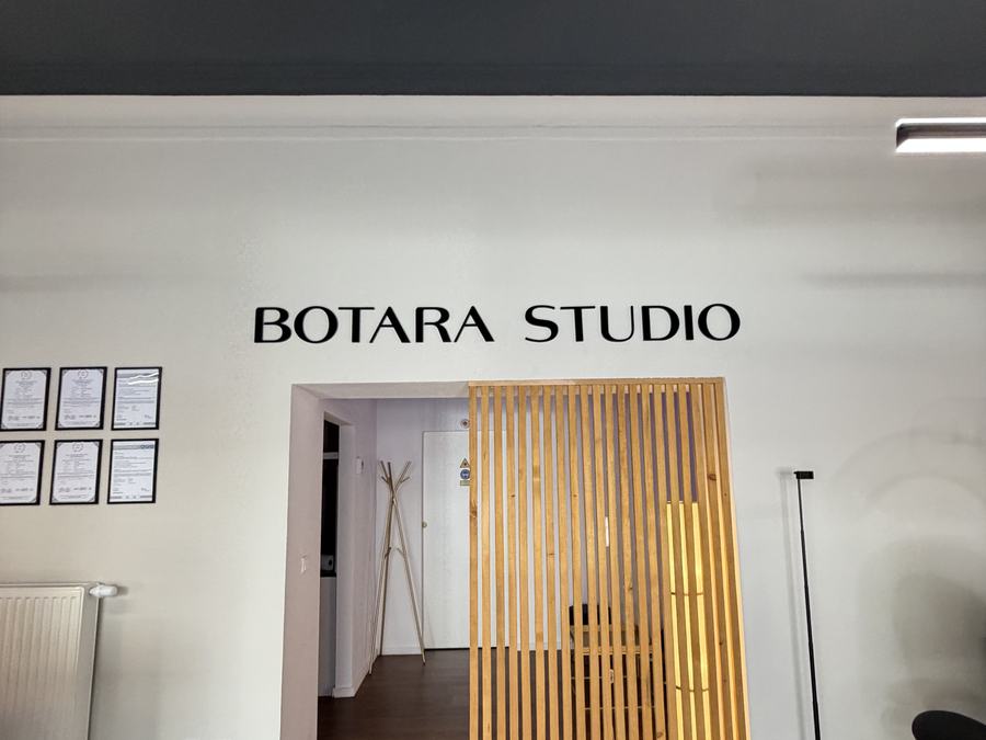 BOTARA-Studio-Wandschriftzug über dem Durchgang mit Holzlamellen-Trennwand