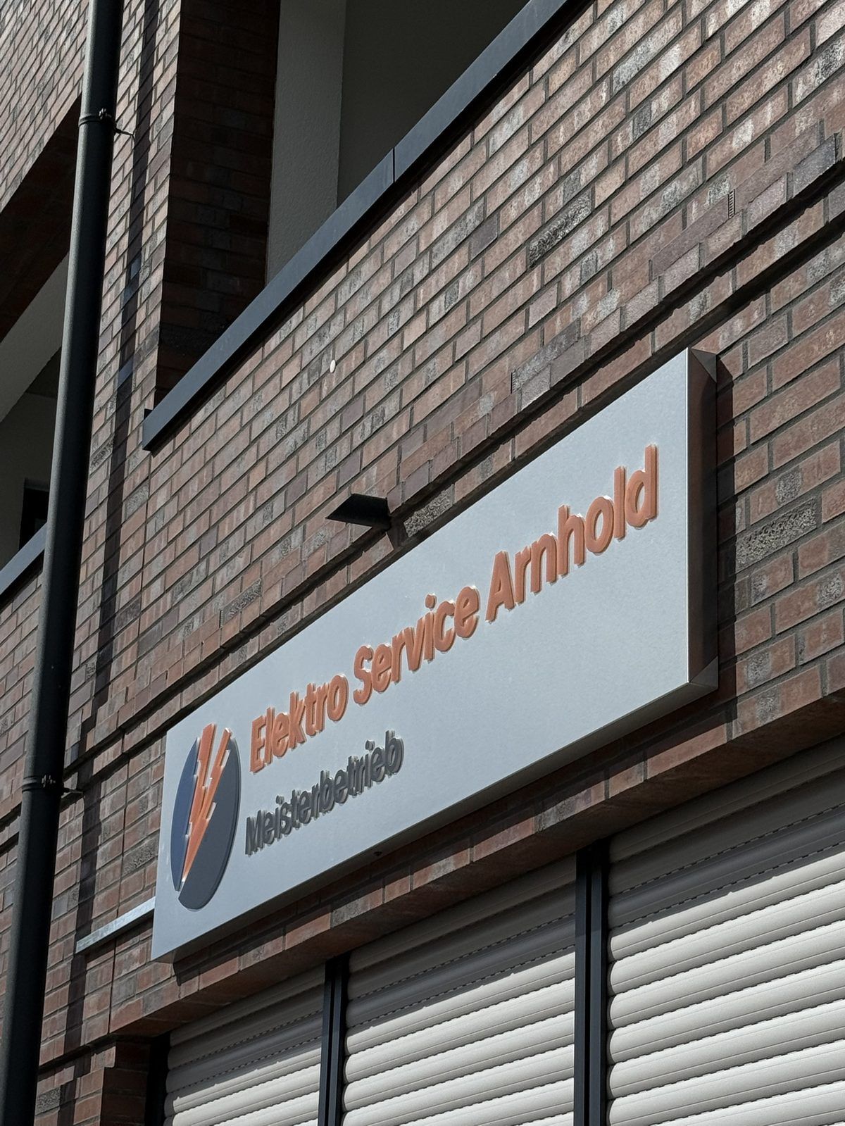 Detailansicht der orangefarbenen 3D-Buchstaben und des Blitz-Logos von Elektro Service Arnhold in Buldern, reale Umsetzung von Visuellewand