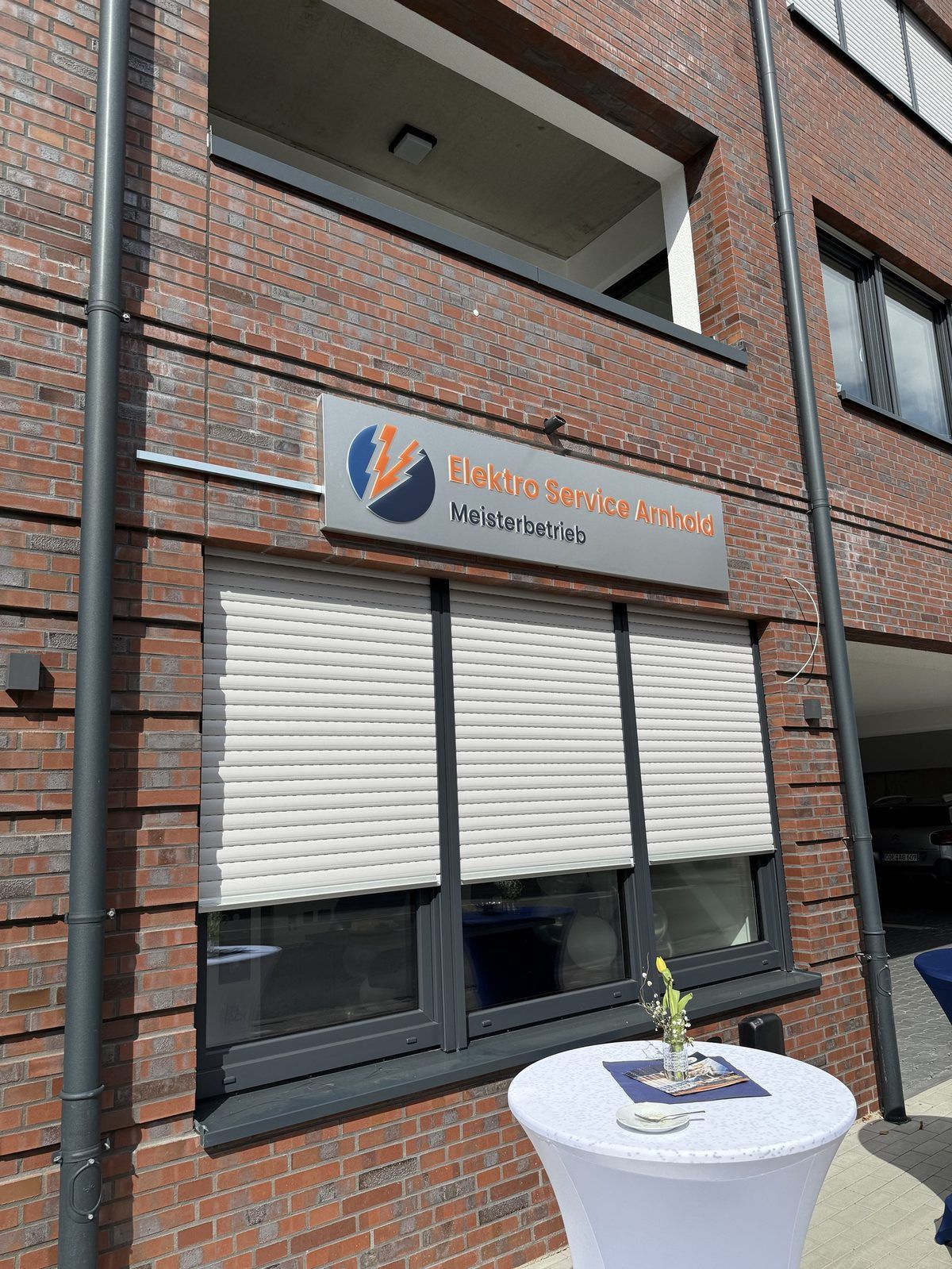 Seitliche Ansicht des Wandschildes von Elektro Service Arnhold an der Klinkerfassade, reale Umsetzung von Visuellewand