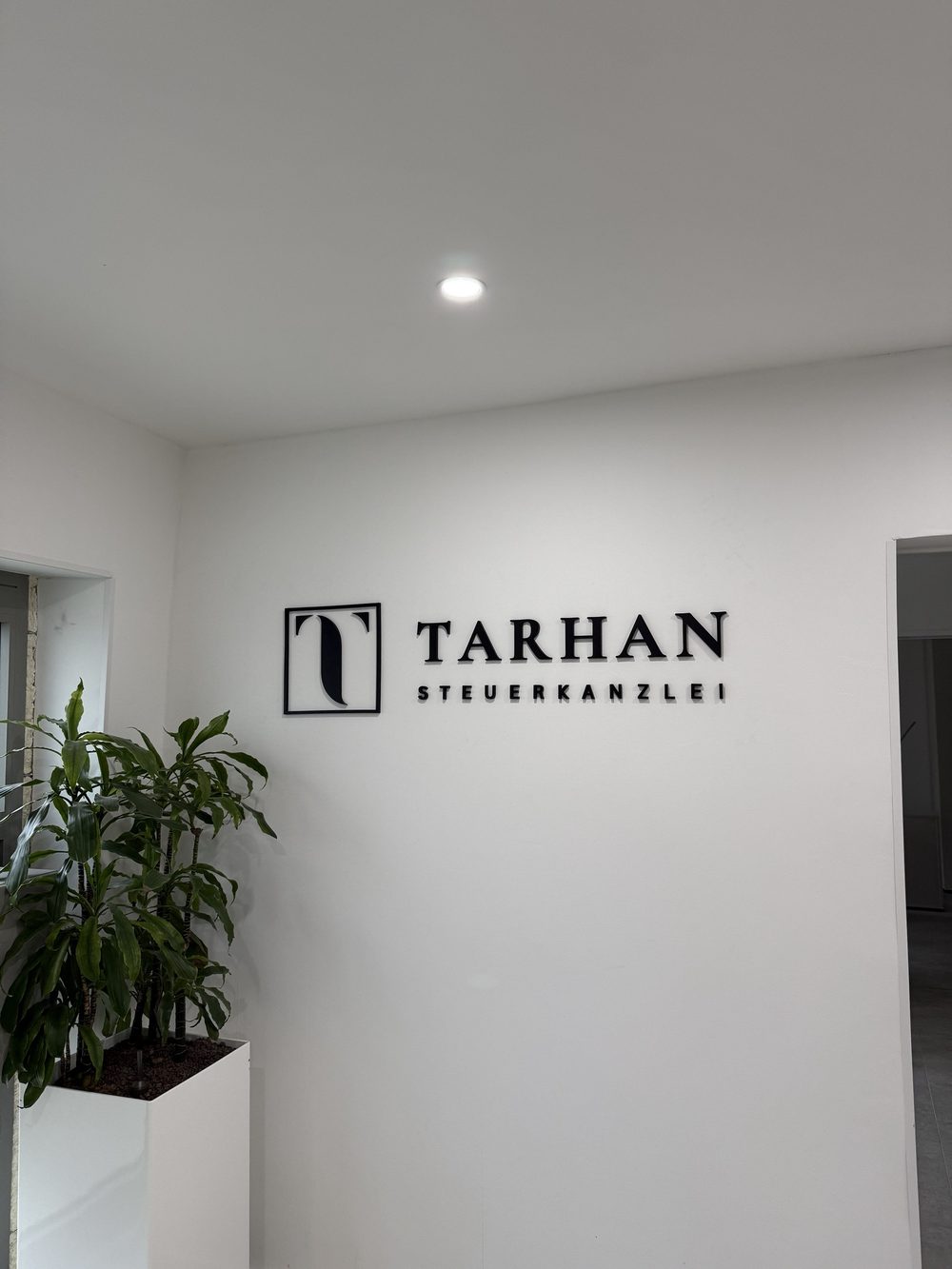 Empfangsbereich der Tarhan Steuerkanzlei in Oberhausen mit dem individuellen 3D-Wandlogo und Blick auf die angrenzenden Räume
