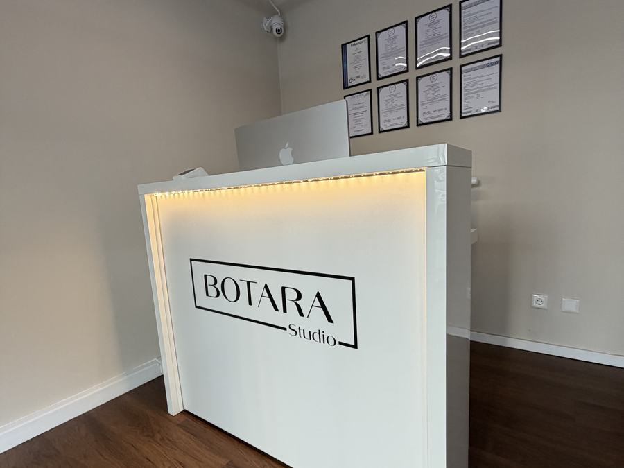 Empfangstheke mit BOTARA-Studio-Logo und Zertifikaten im Hintergrund