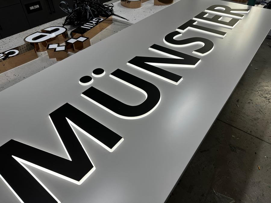 Nahaufnahme der hinterleuchteten Buchstaben MÜNSTER mit Umlaut-Punkten, Teil der Außenreklame für AS-Floor Vinyl Depot
