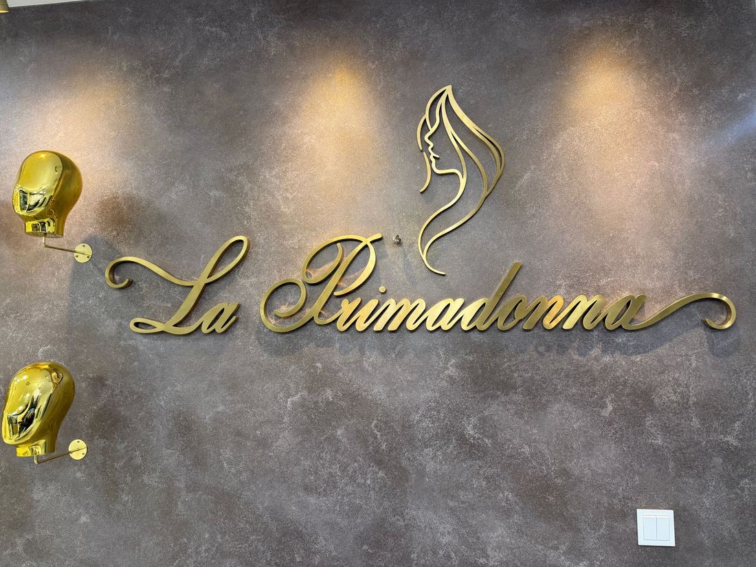 Nahaufnahme des goldfarbenen 3D-Wandlogos "La Primadonna" auf der Steinoptik-Wand