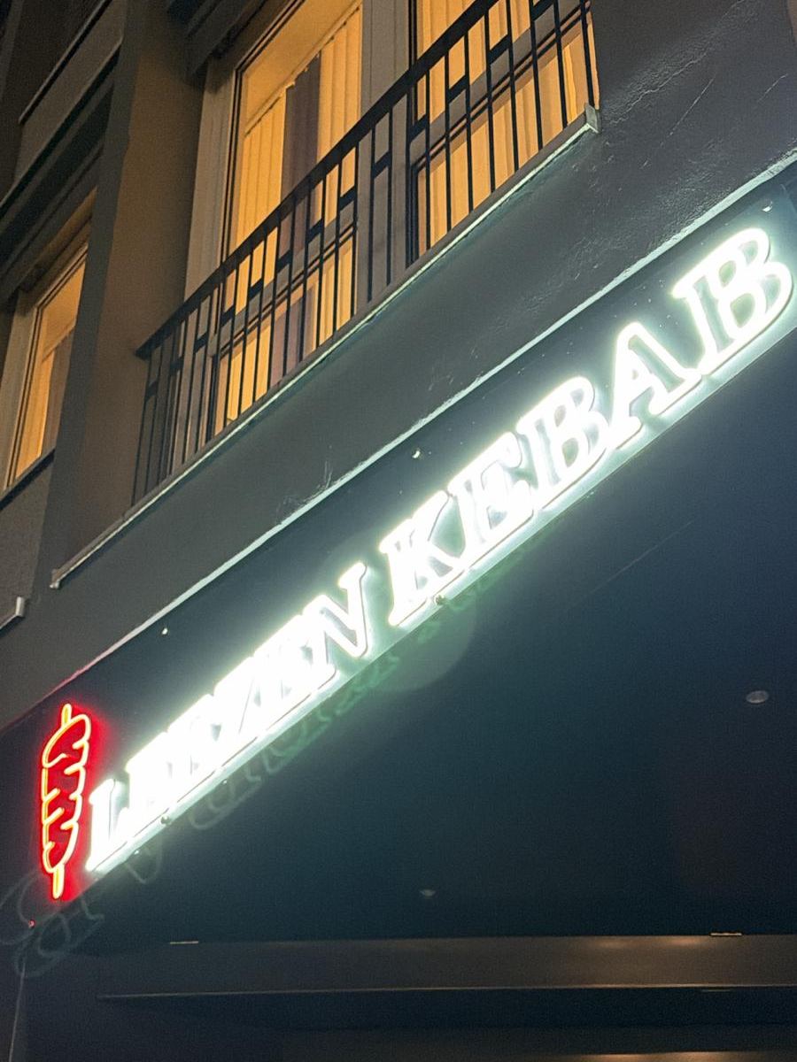 Nahaufnahme des LED-Neon-Schriftzugs LEEZEN KEBAB mit rotem Döner-Symbol bei Nacht