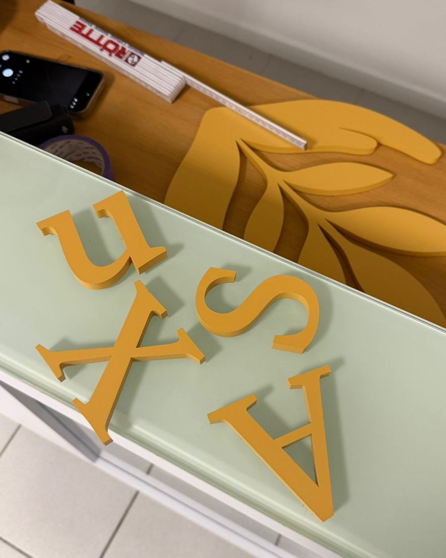 Nahaufnahme einzelner gefertigter Buchstaben des FemNatur-Praxis-Logos vor der Montage