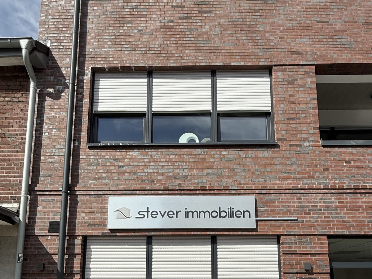 Stever-Immobilien-Wandschild an der Klinkerfassade in der Gesamtansicht, reale Umsetzung von Visuellewand