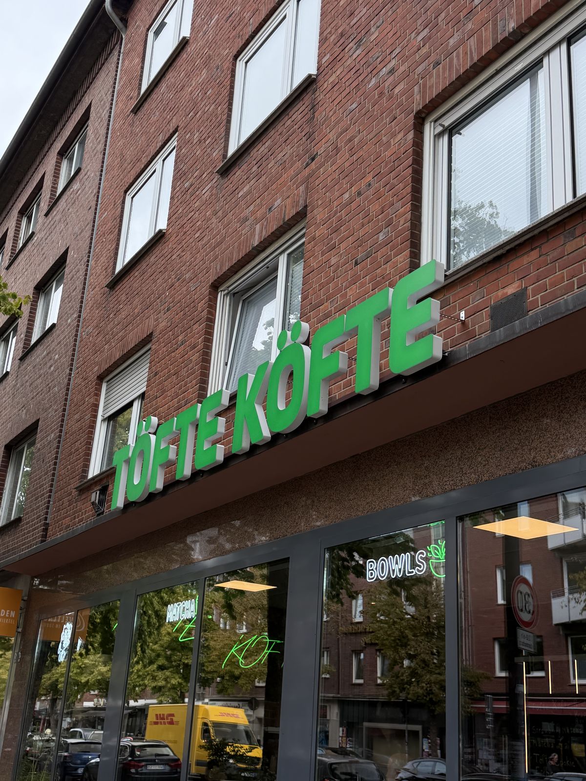 LED-Neon-Schild „Enjoy“ mit Maskottchen im Schaufenster bei Dämmerung, Töte Köfte, Münster
