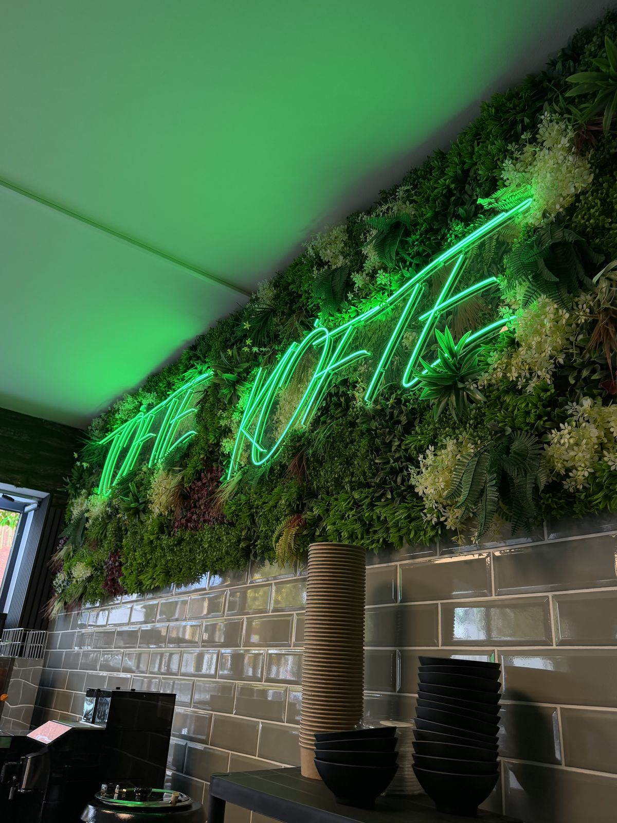 4 Meter langer grüner LED-Neon-Schriftzug „Töfte Köfte“ auf Kunstpflanzenwand im Innenraum, Töte Köfte, Münster