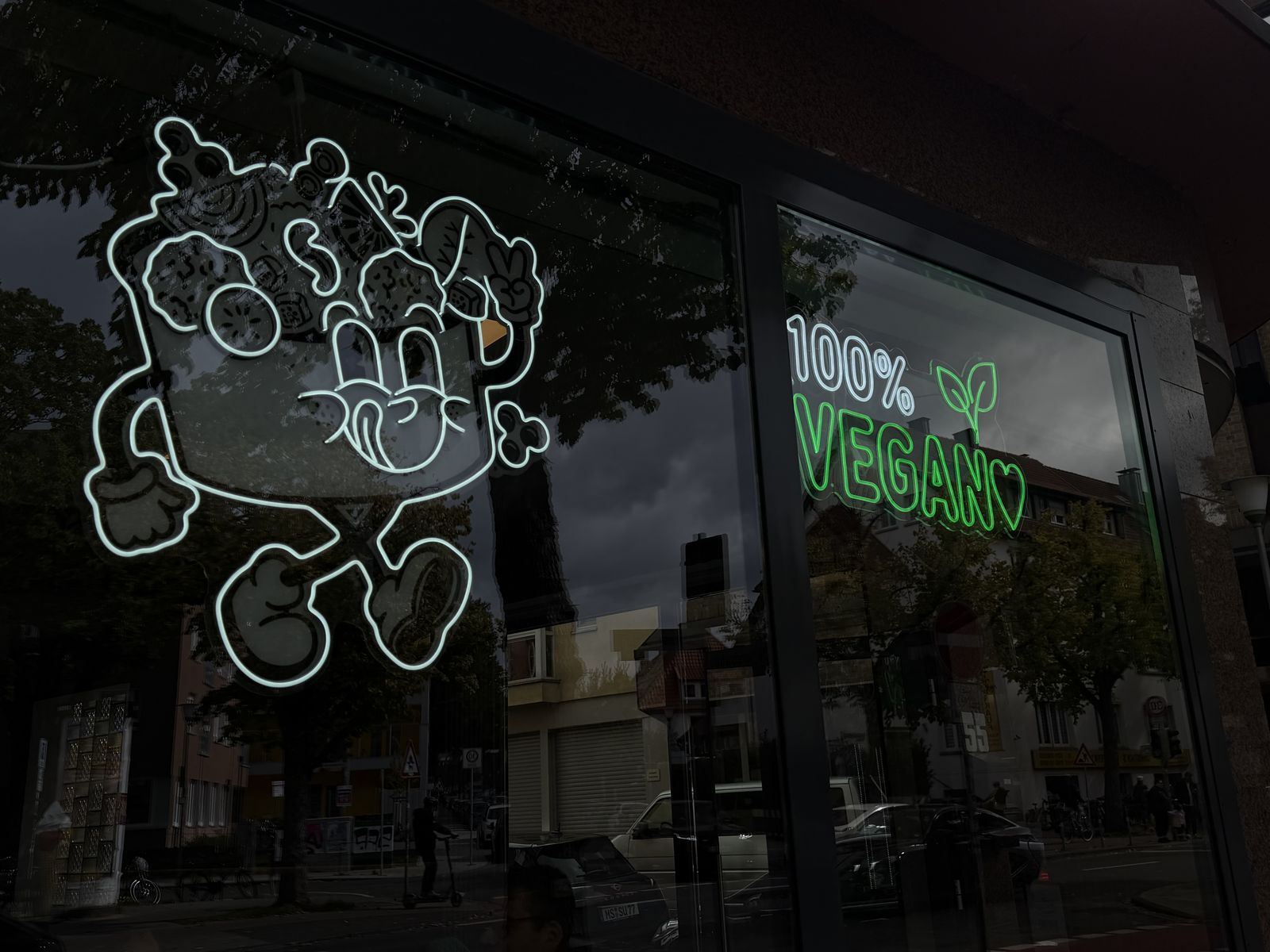 Rundes beleuchtetes Formkasten-Schild mit Vegan-Maskottchen am Haupteingang von Töte Köfte, Münster