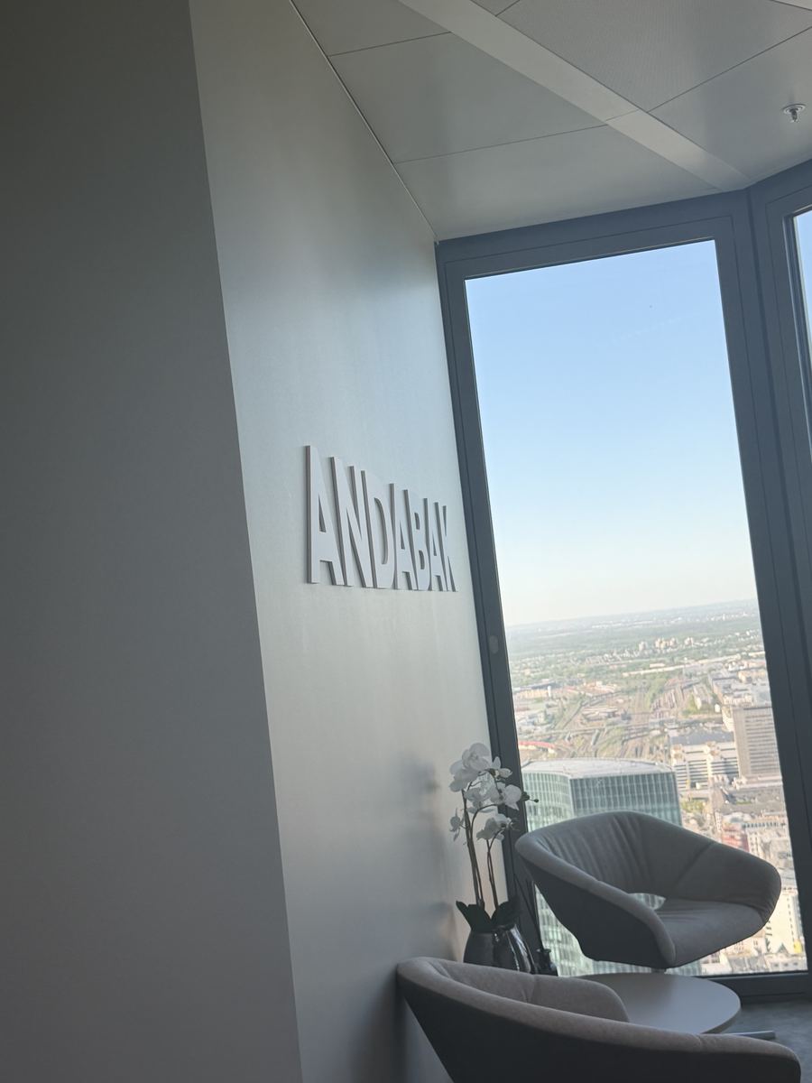 Weiterer Blick auf das 3D-Wandlogo „ANDABAK" an der Eckwand im Büro im 10. Stock des Hochhauses „The Four" in Frankfurt am Main, mit Sitzgelegenheiten und Panoramablick auf die Stadt